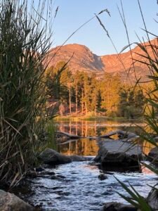 sunrise at a lake in Rocky mountain national park with mountains glowing in the background